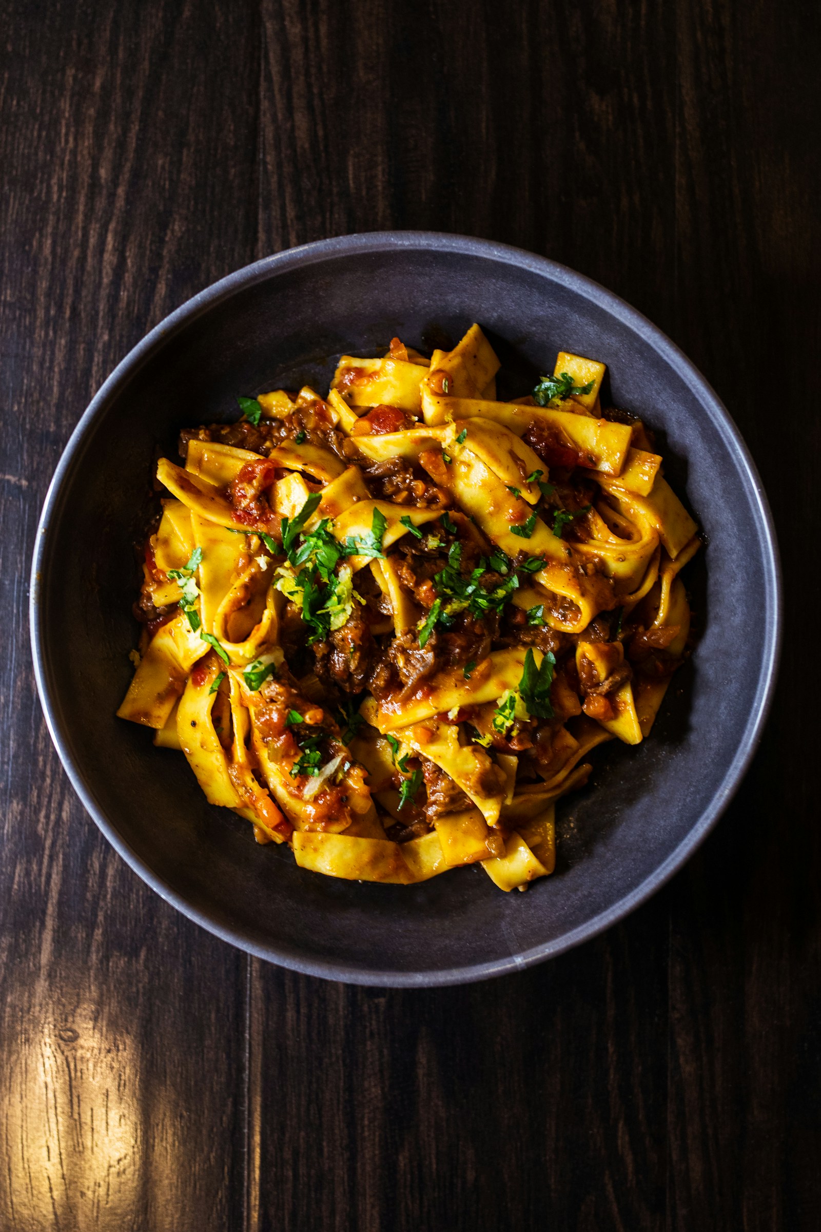 Pasta with tomato sauce and fresh herbs, served in a dark bowl